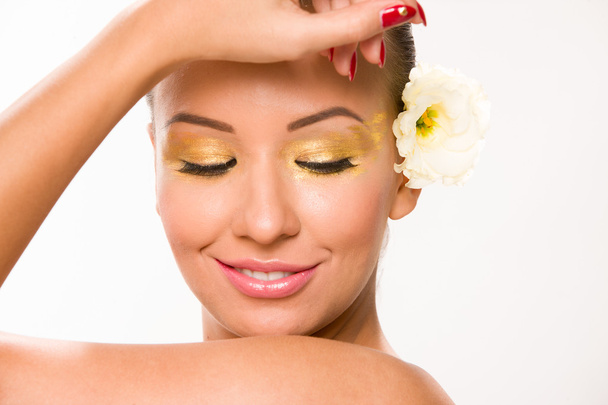 Maquillage en or. Brun cheveux lisses belle femme avec fleur blanche
 - Photo, image