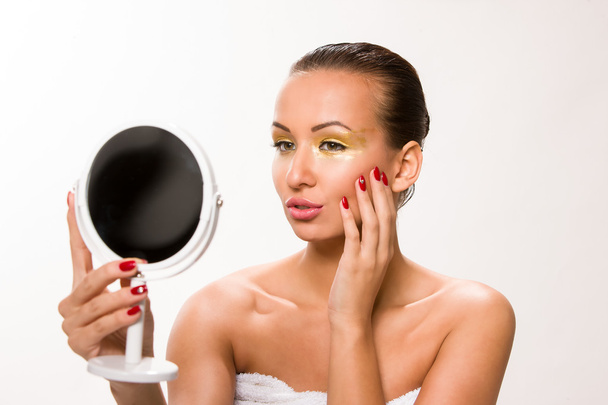 Złoty makijaż. Brązowy elegancki włosy piękna kobieta patrząc w lustro - Zdjęcie, obraz
