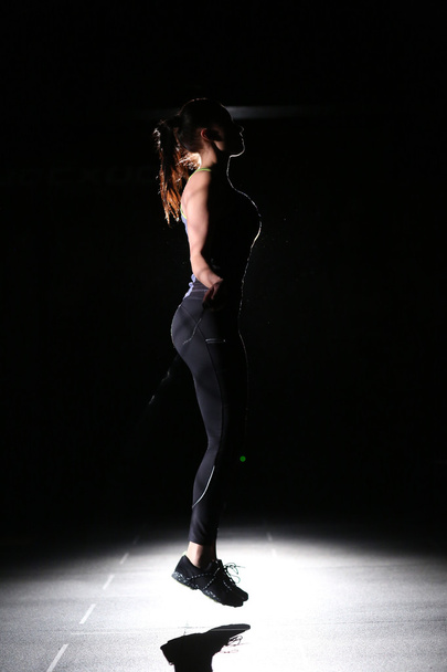 Profile of athletic girl with skipping rope on black background. - Foto, immagini