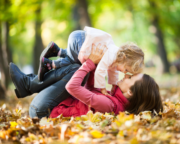 Mulher com criança se divertindo no parque de outono
 - Foto, Imagem