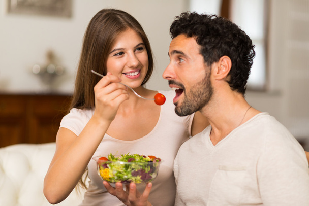 リビング ルームでサラダを食べるカップル - 写真・画像