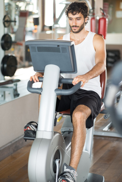 Man working out on stationary bike - 写真・画像
