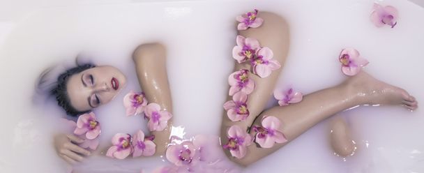 nude model under milk with flowers - Photo, Image