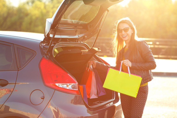 Caucasian woman putting her shopping bags into the car trunk - Foto, immagini