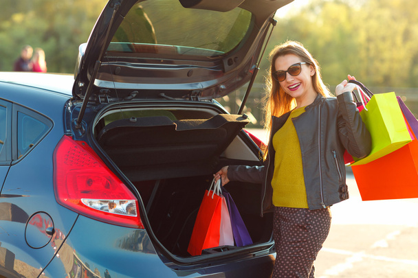 Femme caucasienne mettre ses sacs à provisions dans le coffre de la voiture
 - Photo, image