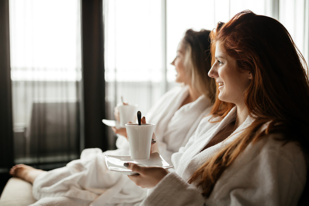 Women in bathrobes enjoying tea - 写真・画像