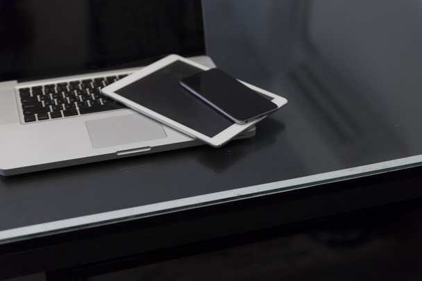 dizüstü bilgisayar, dijital tablet ve siyah masa üstünde hareket eden telefon - Fotoğraf, Görsel