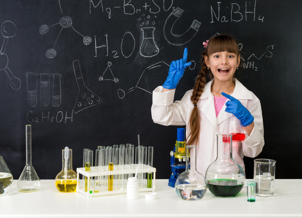 schoolgirl in chemistry lab pointing at formula on blackboard - Фото, зображення