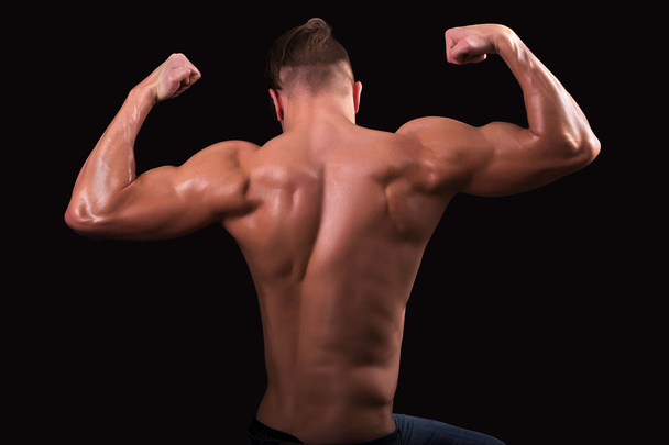 aantrekkelijke bodybuilder sportman toont perfect lichaamsspieren op zwarte achtergrond; Fitness mens; Bodybuilding en fitness sport; atleet kerel; - Foto, afbeelding