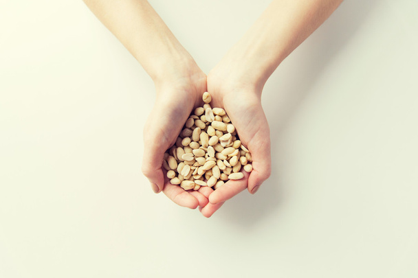 close up of woman hands holding peeled peanuts - Foto, Imagem