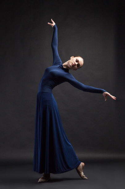 Posing dancer in blue dress over dark background - Photo, Image