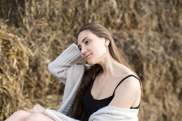 Young pretty woman sitting on straw bales  - Foto, Imagen