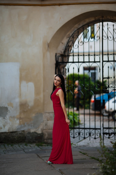 Beautiful model passes through the city on foot. Looking around city.Girl with red lipstick. Elegant lady in beautiful dress - Foto, afbeelding