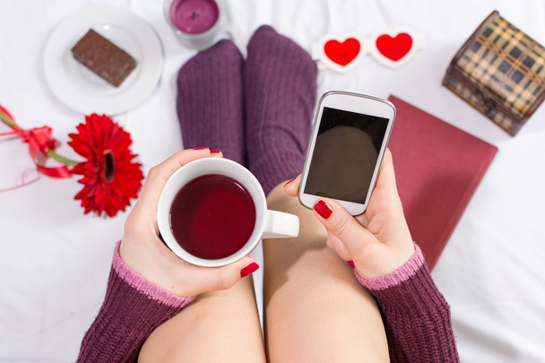 Vrouw met een kopje thee en SMS - Foto, afbeelding