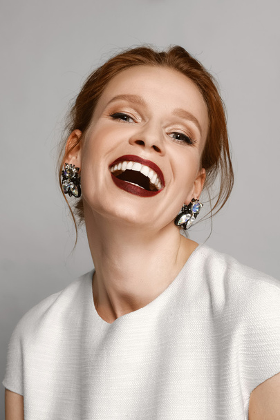 laughing model with red mat lips and gemstone earrings - Valokuva, kuva