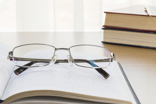 Eyeglasses put on notebook on wood table - Foto, Imagem