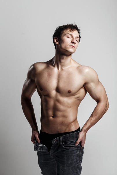 Muscular male model bodybuilder with unbuttoned jeans. Studio sh - Zdjęcie, obraz