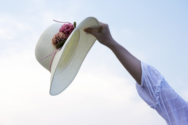 Καπέλο στο χέρι γυναίκα στην παραλία - Φωτογραφία, εικόνα