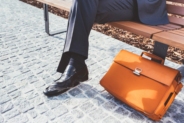 businessman sitting on a bench with briefcase - Foto, Imagen