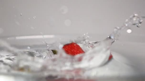 Drie aardbeien laten vallen in water - Video