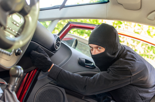 κλέφτης στη μάσκα που σπάζει την πόρτα στο αυτοκίνητο - Φωτογραφία, εικόνα