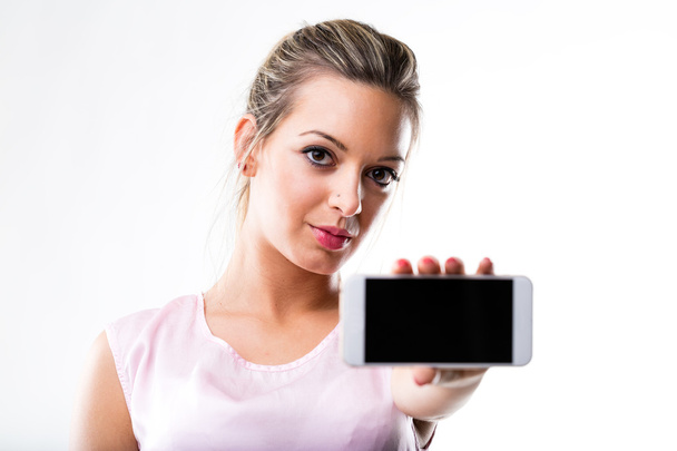 mujer (en foco) sosteniendo un teléfono móvil (fuera de foco
) - Foto, Imagen