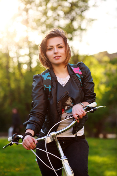 Dreamy young woman on bicycle in green park on sunset - Foto, immagini