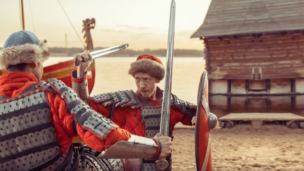 Битва два середньовічних лицарів з мечами та щити. Військовий корабель  - Фото, зображення