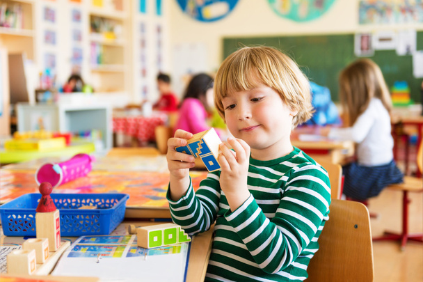 Innenporträt eines niedlichen kleinen Jungen in einem Klassenzimmer - Foto, Bild