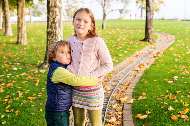 Kaksi ihanaa lasta leikkii puistossa kauniina syyspäivänä.
 - Valokuva, kuva