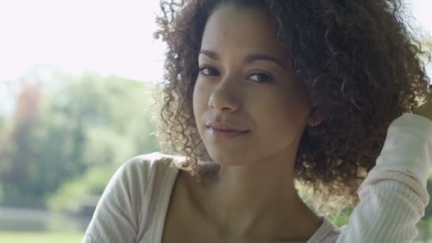 Closeup portrait of a beautiful mixed race woman smiling warmly to a camera. - Imágenes, Vídeo