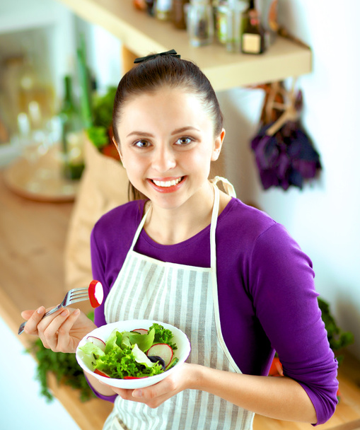Mladá žena jíst čerstvý salát v moderní kuchyni - Fotografie, Obrázek