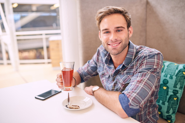Good looking man looks straight at camera sitting in cafe - Photo, image