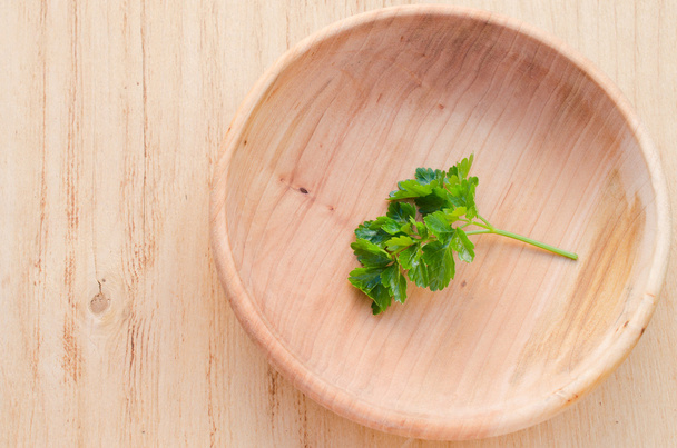 Sprig of fresh green parsley in a wooden plate - Fotó, kép