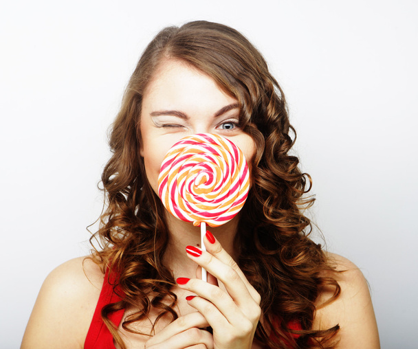 portrait of a smiling cute girl covering her lips with lollipop - Фото, зображення