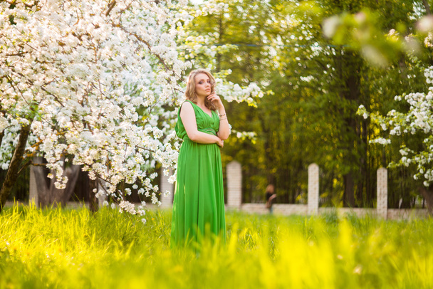 Beautiful happy young woman in spring blossoming garden - Фото, изображение