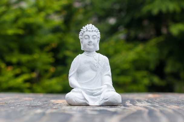 Budda - statuetka ceramiczna budha na zielonym tle. Buddyzm, medytacja, joga koncepcja - Zdjęcie, obraz