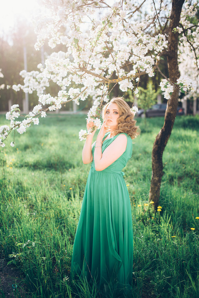 красивая молодая блондинка, стоящая рядом с цветущим яблоней
 - Фото, изображение