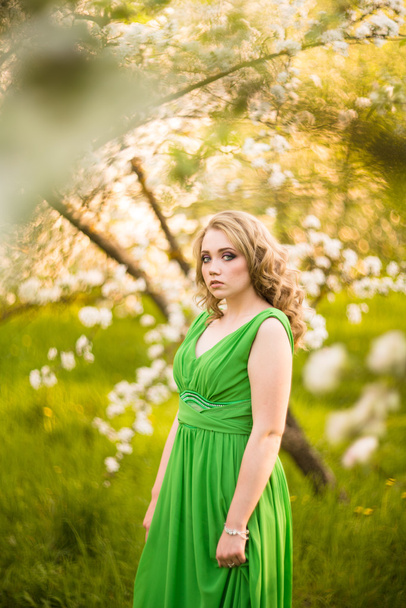 beautiful young blond woman standing beside a blossoming Apple tree - Valokuva, kuva