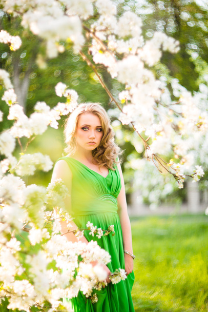 Beautiful happy young woman in spring blossoming garden - Photo, image