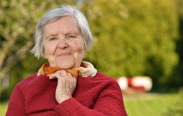 Donna anziana sorridente e sognante in giardino
 - Foto, immagini