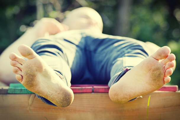 Man with dirty feet lies and relaxes - 写真・画像