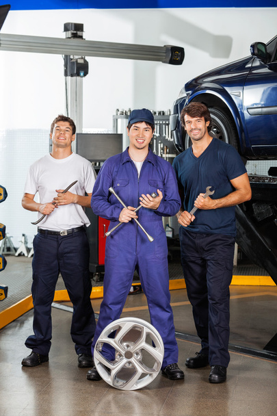 Happy Mechanics Holding Wrenches At Garage - Фото, изображение