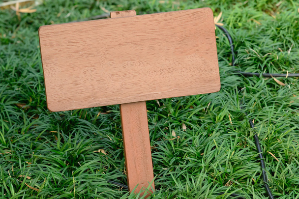 Letrero de madera marrón contra fondo de hierba
 - Foto, Imagen