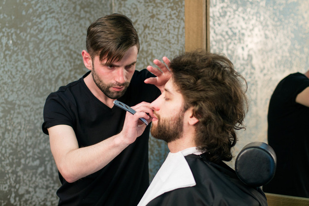  A barber  shaving man's beard - Photo, Image