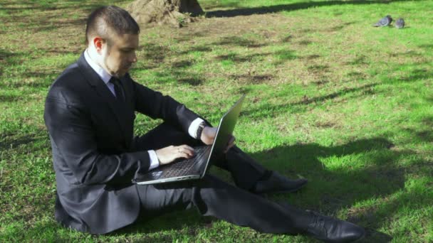 Biznesmen współpracuje z laptopa w parku miejskim - Materiał filmowy, wideo