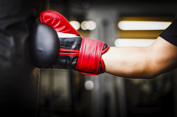 Punching ένα σάκο ζουμπάρισμα με τα κόκκινα γάντια του μποξ - Φωτογραφία, εικόνα
