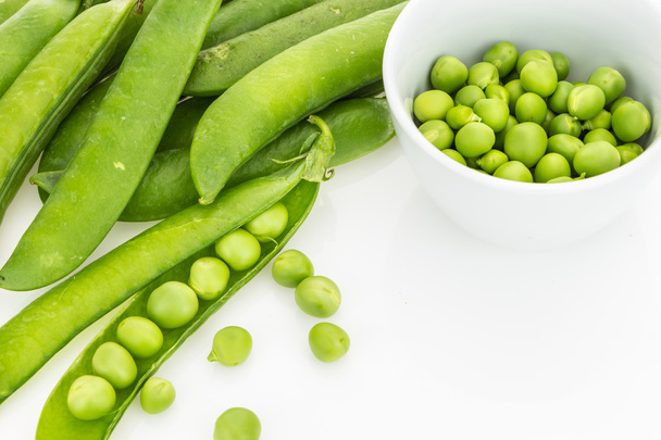 新鮮な緑のエンドウ豆の鞘と白い背景の上のボウルに豆 - 写真・画像