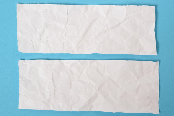 white ripped pieces of news paper on on blue background. - Foto, imagen