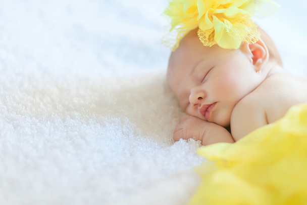 Menina recém-nascida está dormindo em saia amarela com chapéu
 - Foto, Imagem